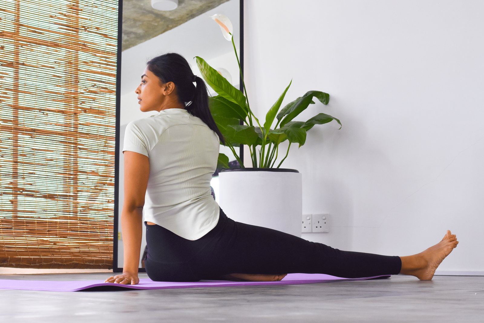 A woman practising a seated yoga stretch inside Svastha Studio